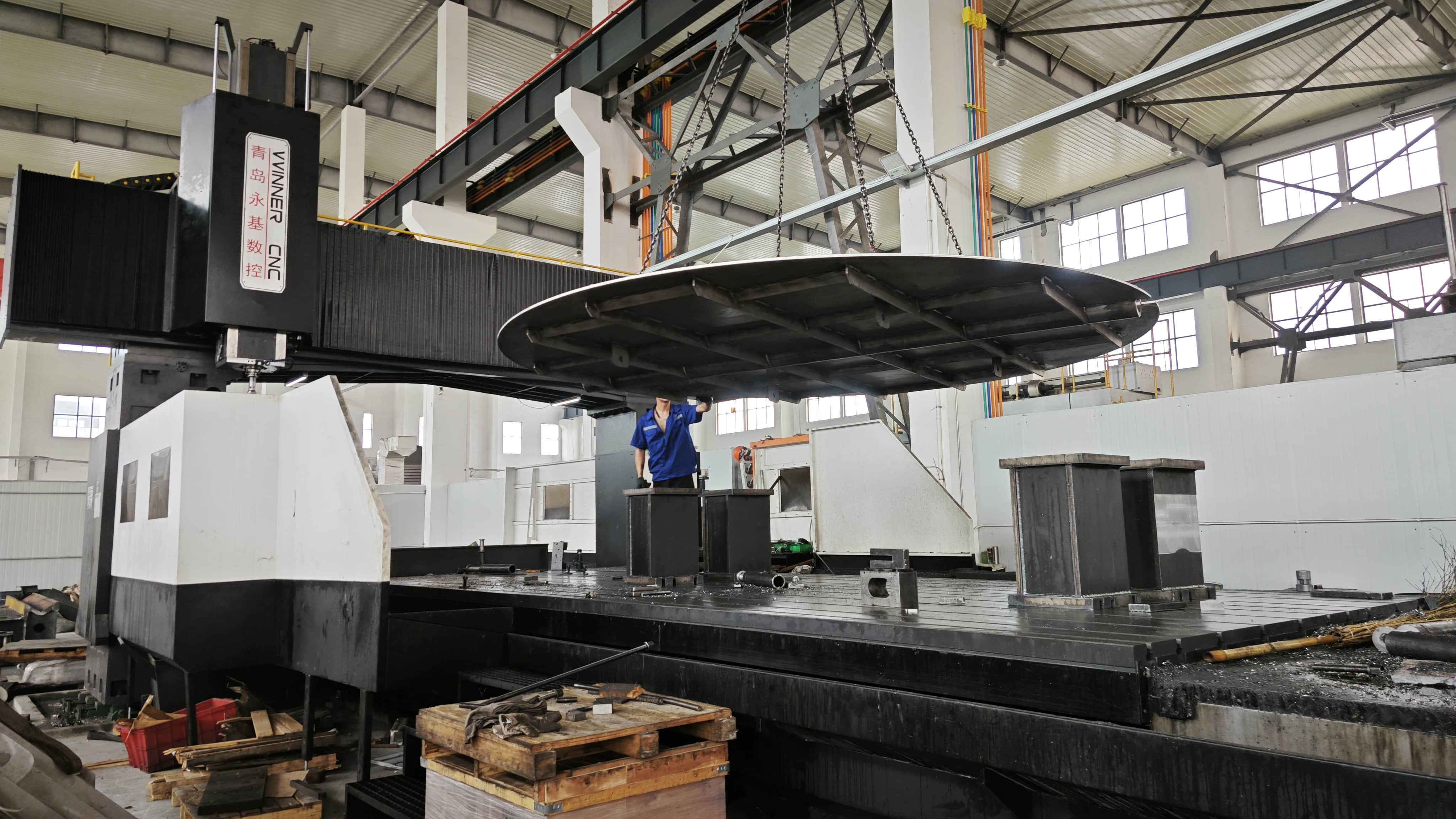 A large gantry CNC machining center processes an extra-large industrial damper disc.
