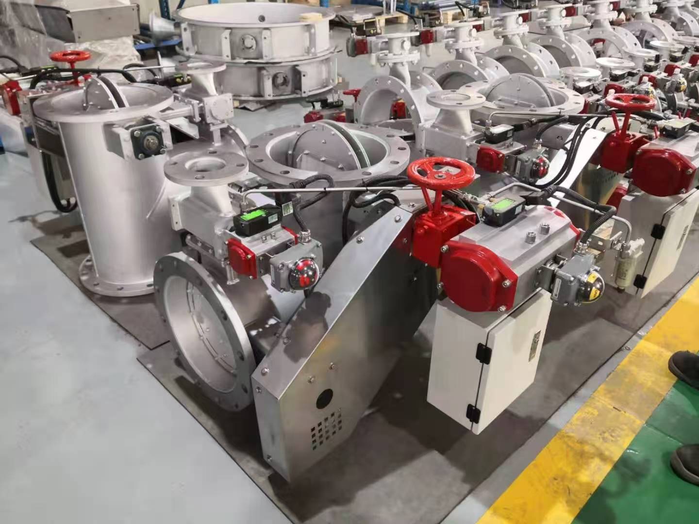 A large batch of stainless steel three way pneumatic diverter valves is placed in the workshop each equipped with a pneumatic actuator manual handwheel and local control box for the RTO systems exhaust switching project