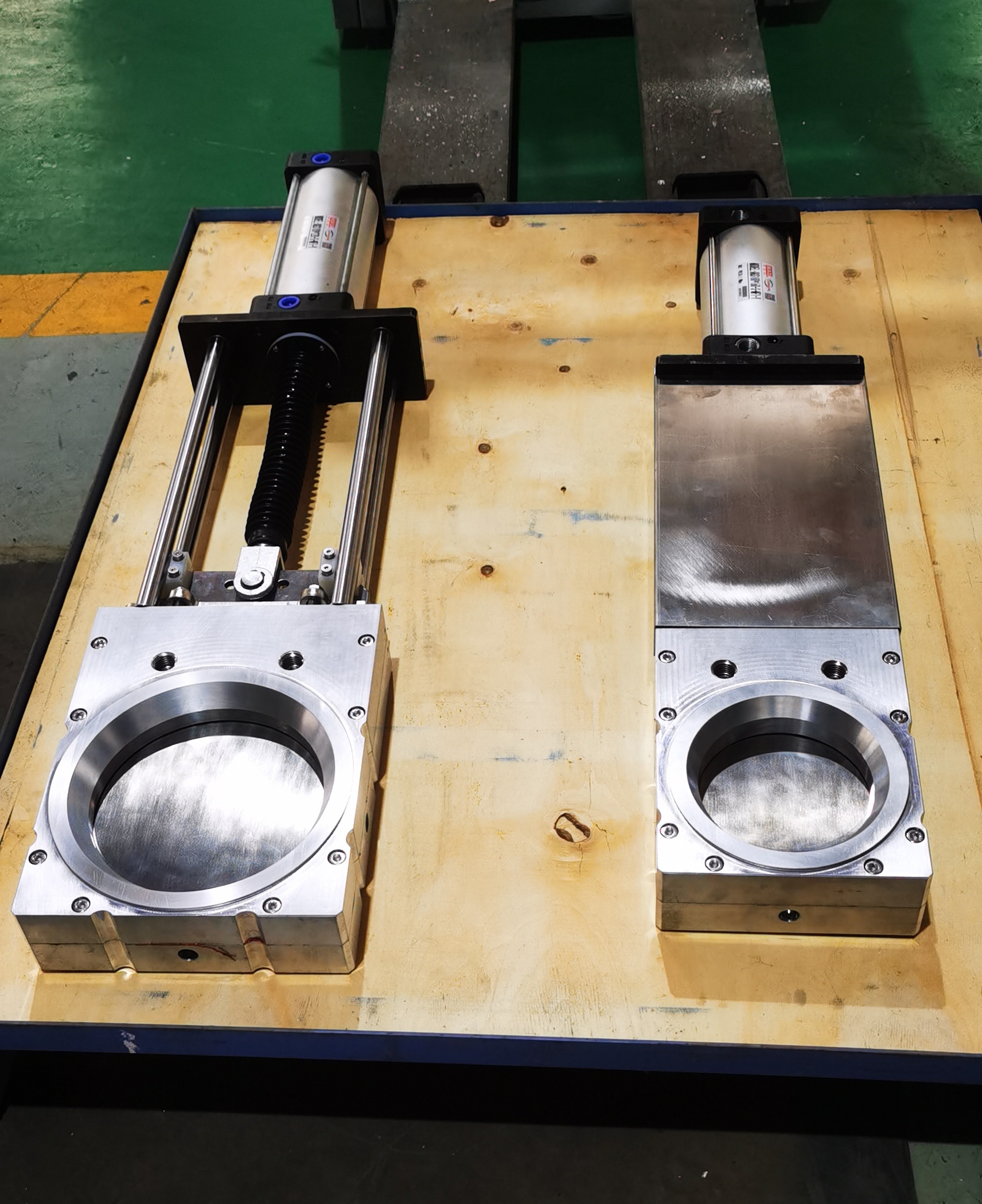 A comparison display of two stainless steel round flange pneumatic guillotine isolation damper equipped with pneumatic actuators used for flue gas isolation in the flue gas purification systems of the waste incineration
